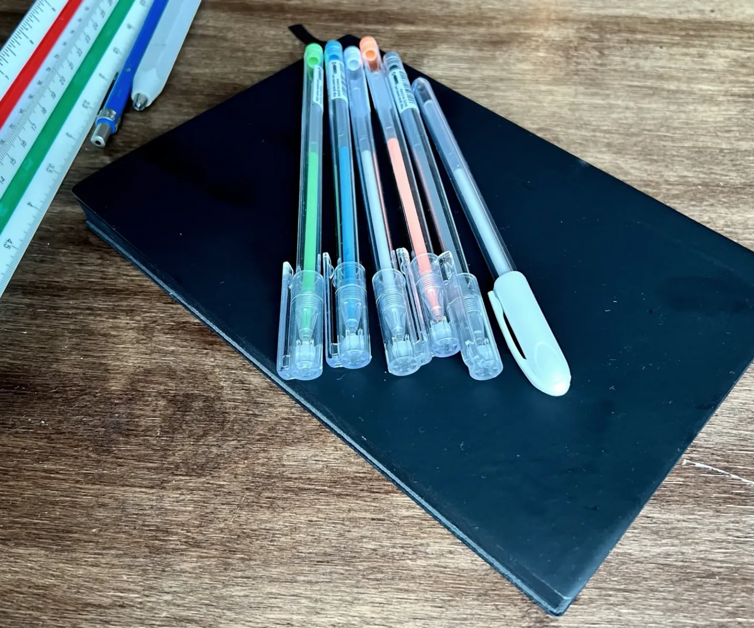 Black Architect's Sketchbook on a desk with colored pens and scales in the background
