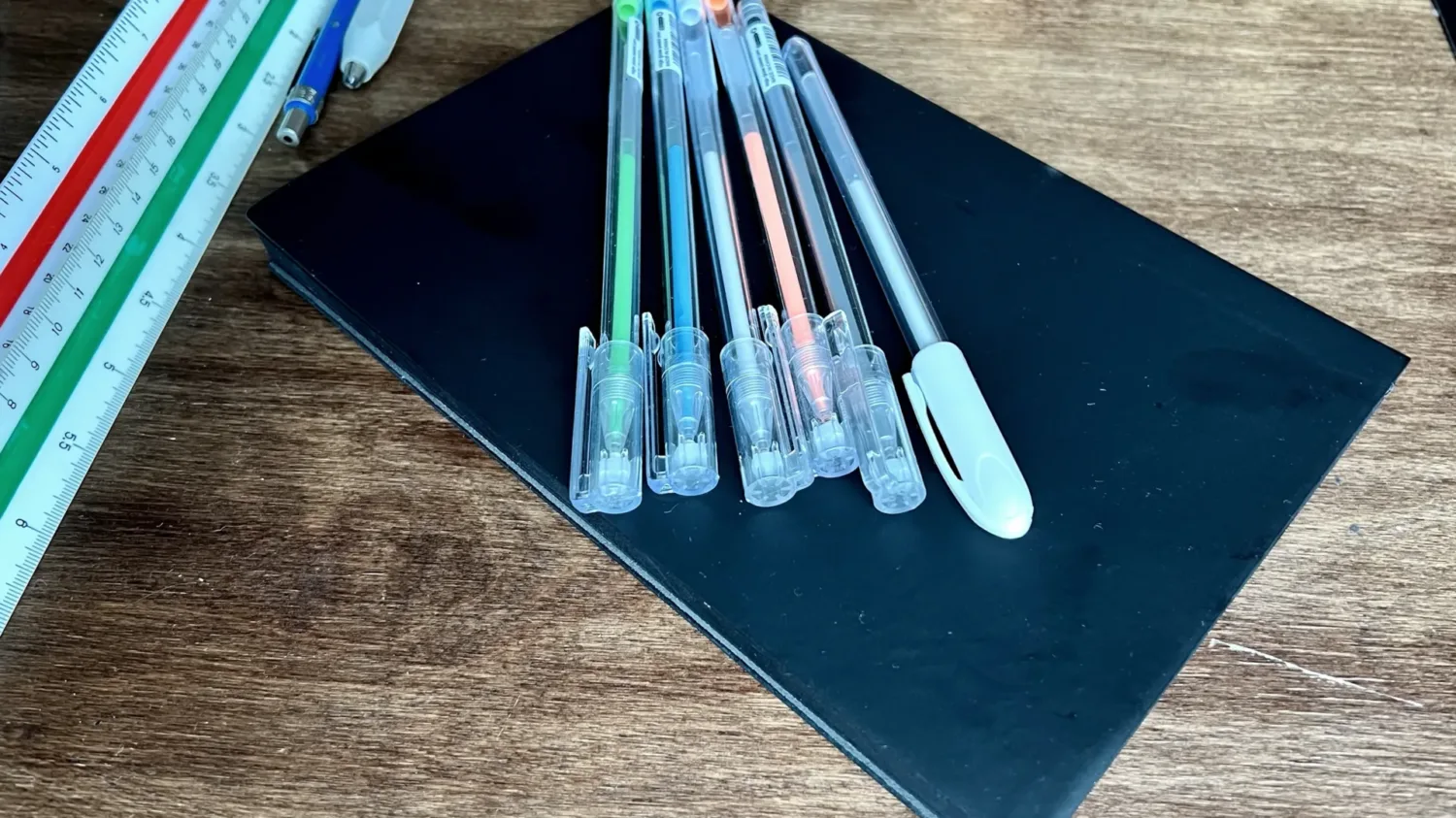 Black Architect's Sketchbook on a desk with colored pens and scales in the background